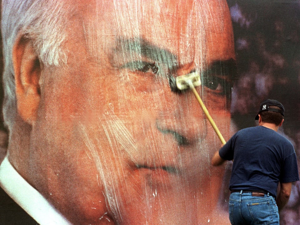 Zu sehen ist das Konterfei des damaligen deutschen Kanzlers Helmut Kohl. Ein Plakatkleber ist dabei, das Plakat zu überkleben.