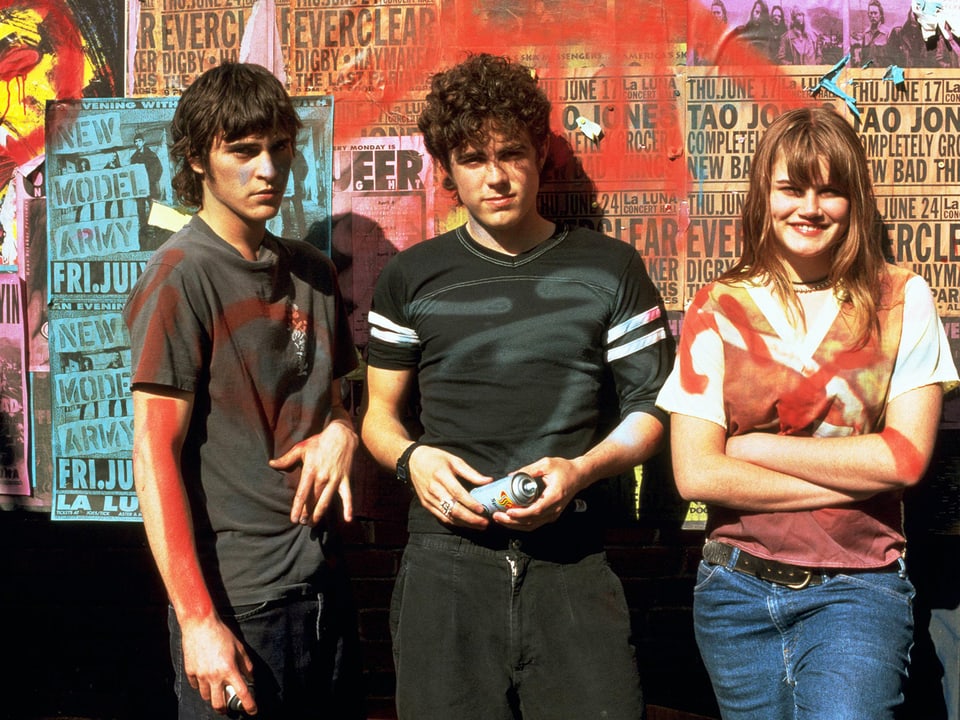 Joaquin Phoenix, Casey Affleck, Allison Folland stehen mit Spraydosen vor einer Wand.