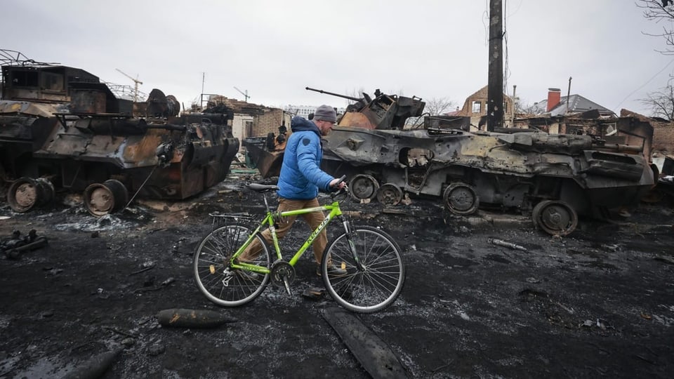 Ein Passant in Butscha unweit der Hauptstadt Kiew passiert zerstörte russische Panzer