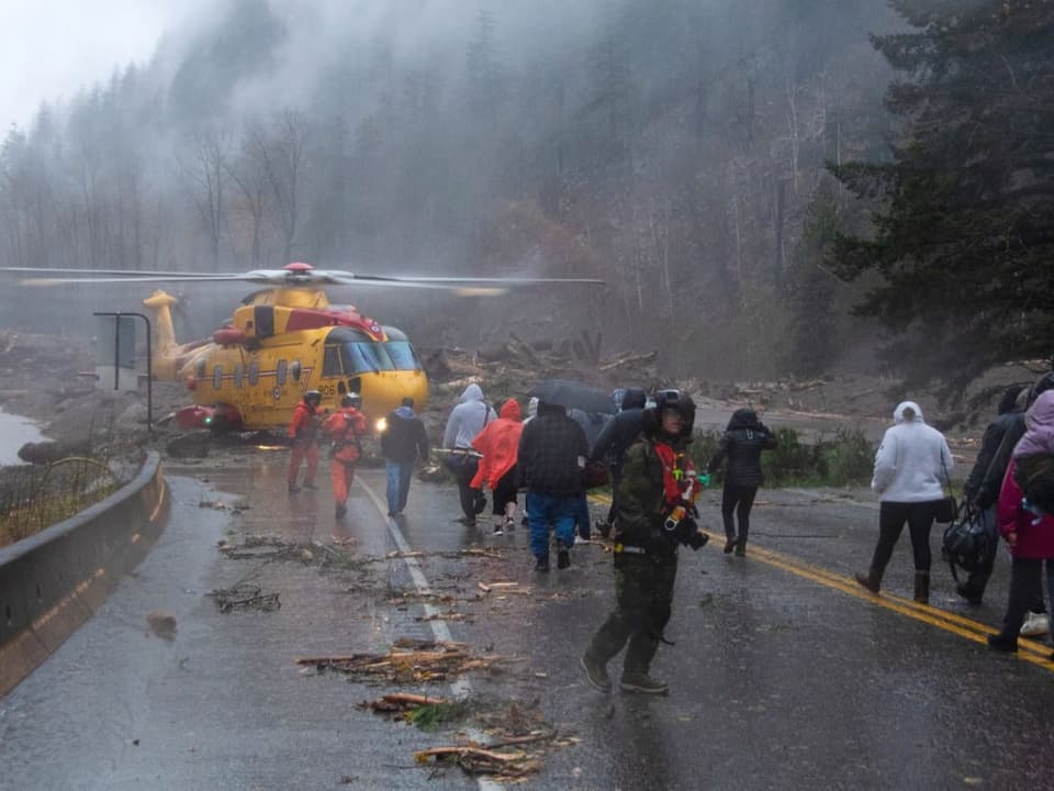 Ein Helikopter holt Menschen von einer bei einem Erdrutsch verschütteten Strasse ab.