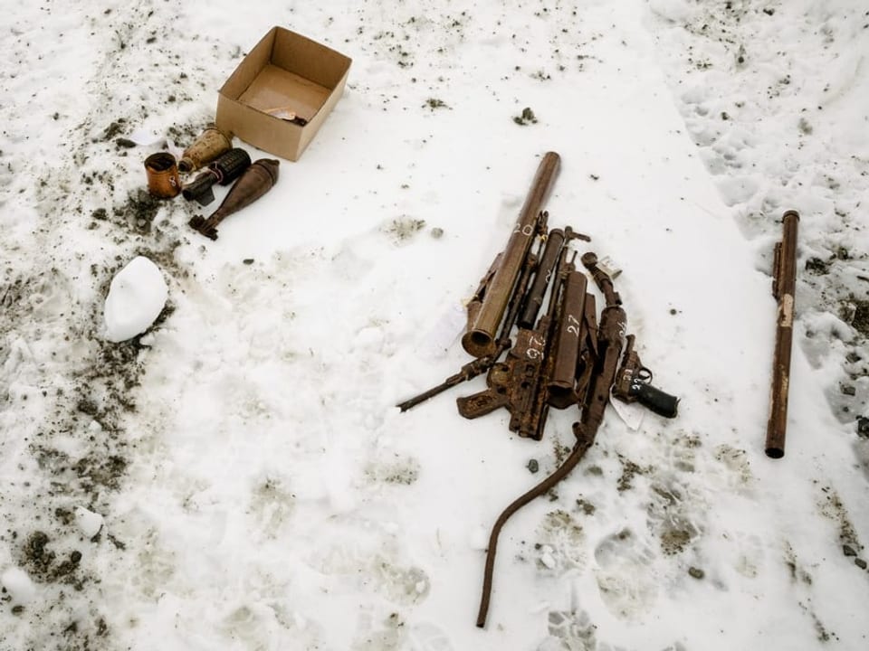 Rostige Waffenteile im Schnee.