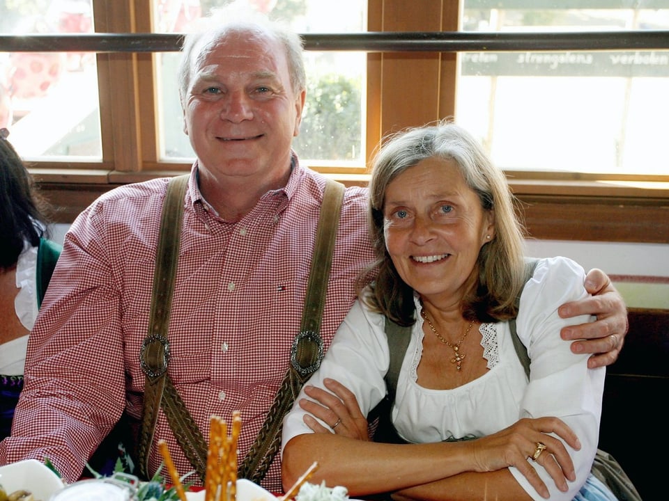 Uli Hoeness (links) mit seiner Frau Susanne sitzend an einem Tisch, bedie tragen bayerische Tracht