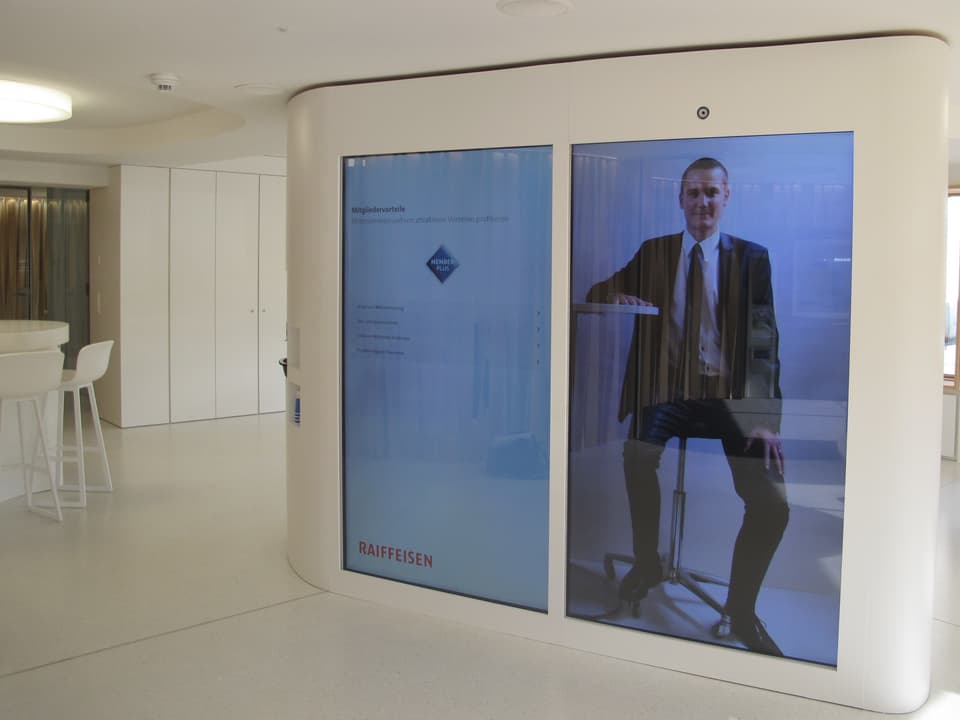 André Picard auf dem grossen Bildschirm in der Schalterhalle der Raiffeisenbank Alchenflüh