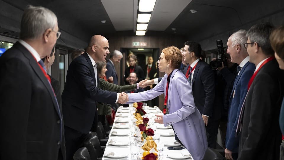 Um einen gedeckten Tisch in einem Zug stehen unter anderem Bundesrat Alain Berset und Ständeratspräsidentin Eva Herzog.