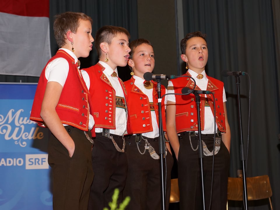 Die vier jungen Sänger in Appenzeller Tracht vor dem Mikrofon beim Singen.