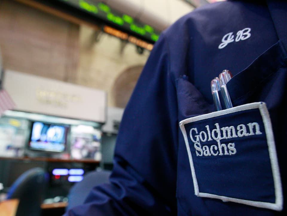Ein Börsenhändler an der New York Stock Exchange (NYSE) mit einem blauen Kittel mit Goldman Sachs-Logo.