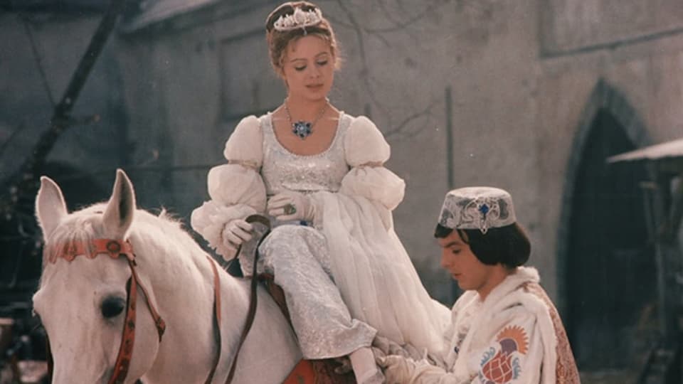 Aschenbrödel sitzt auf dem Pferd, während der Prinz ihr den Schuh anzieht. 