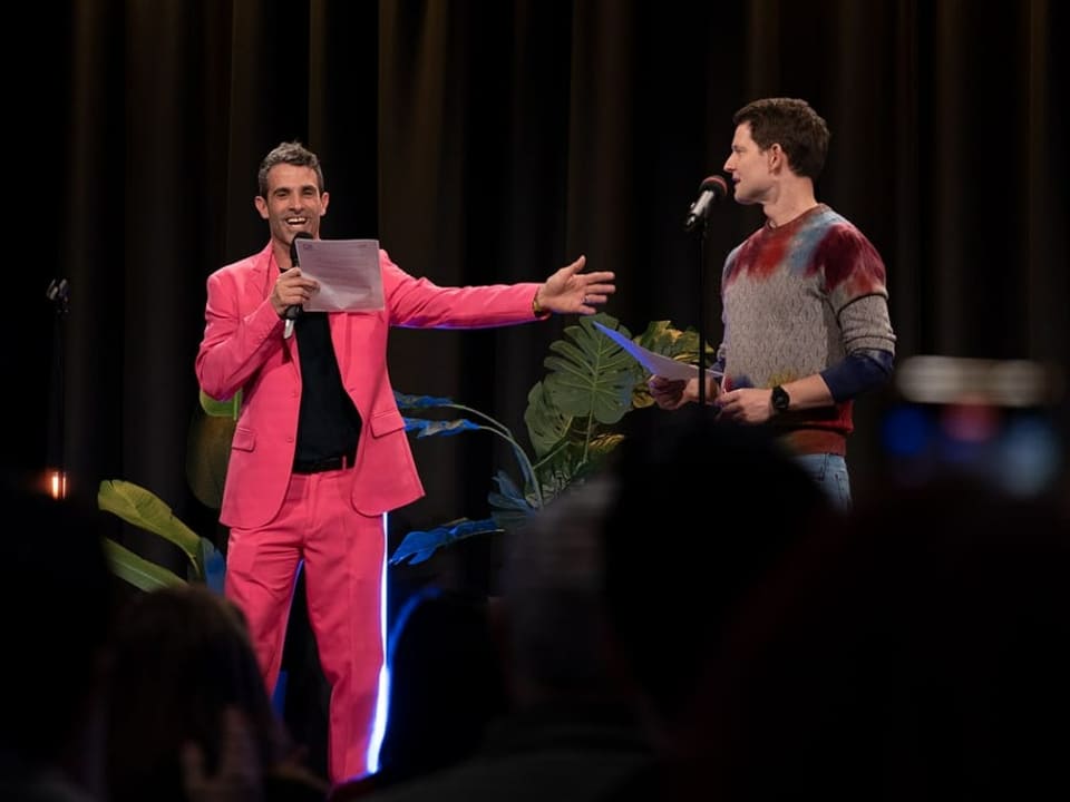 Fabian Unteregger und Philippe Gerber stehen auf der Bühne, während Fabian Unteregger sein Comedy-Programm vorträgt.