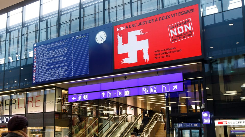 Hakenkreuz-Plakat auf der Werbefläche der Abfahrtstabelle (eBoard) im SBB-Bahnhof Genève.