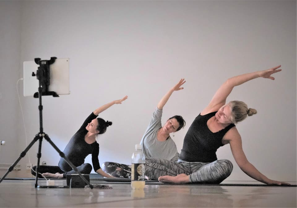 Drei Frauen machen Yogaübungen vor einer Kamera