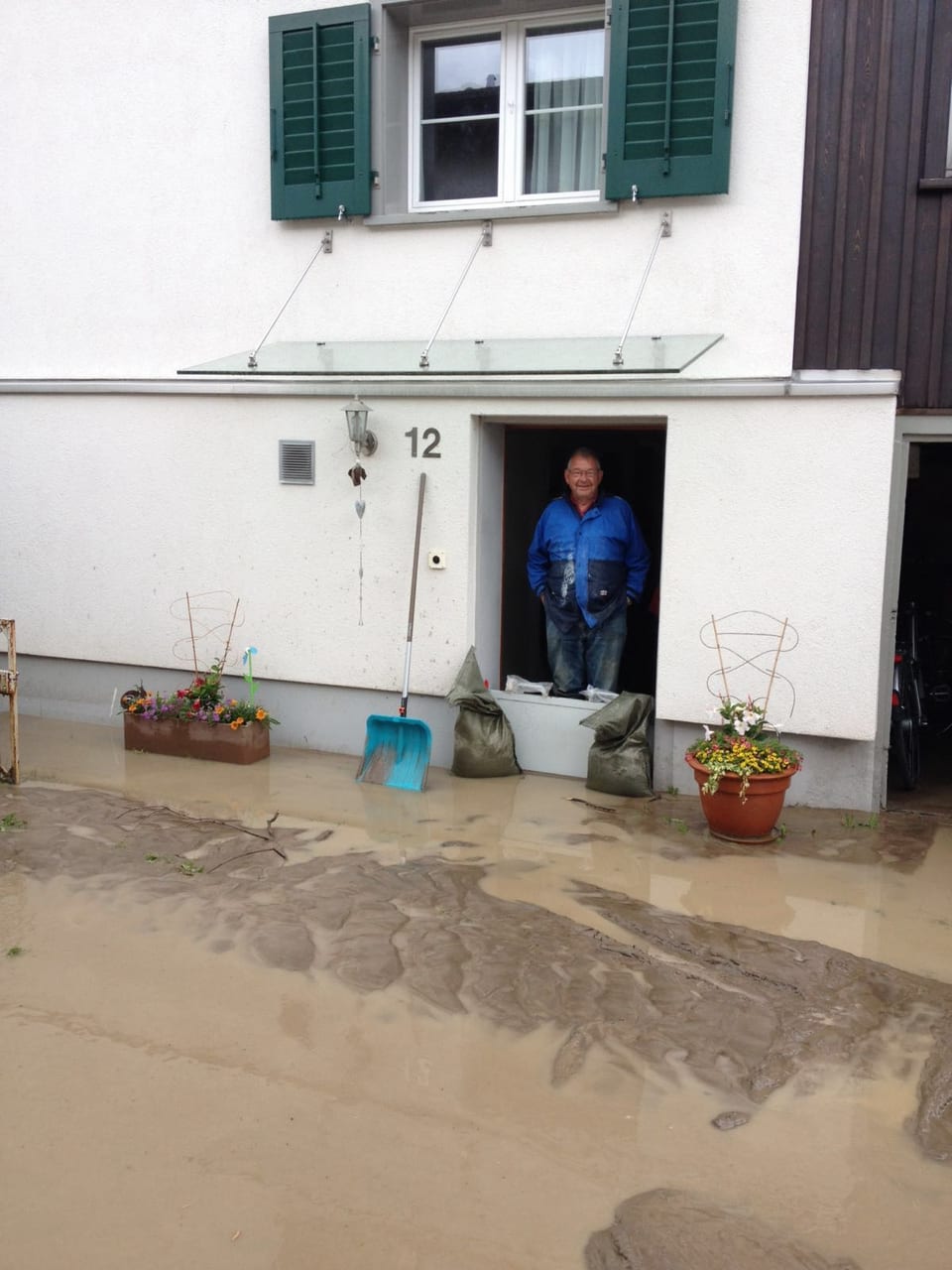Mann steht vor Haus, Wasser am Boden