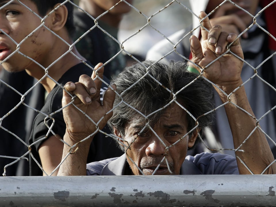 Menschen am Flughafen von Tacloban. Dort stehen sie hinter dem Zaun.