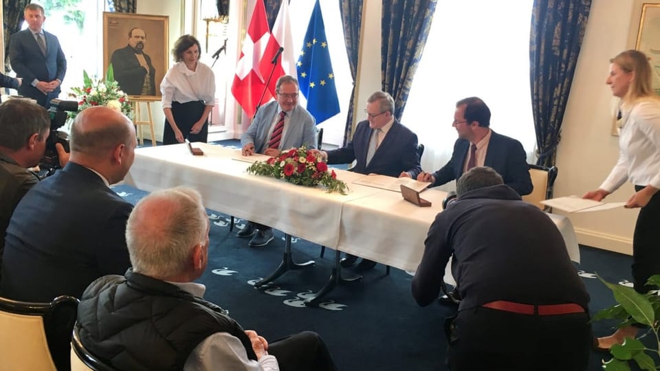 Vertreter aus Polen unterzeichnen ein Schriftstück.
