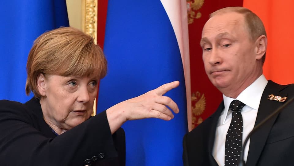 Angela Merkel zeigt mit dem Finger, Wladimir Putin macht ein betretenes Gesicht. 