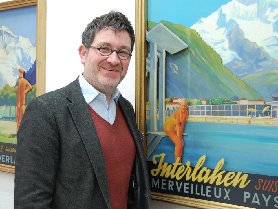 Stefan Otz, Tourismusdirektor von Interlaken, vor einem historischen Werbe-Bild.
