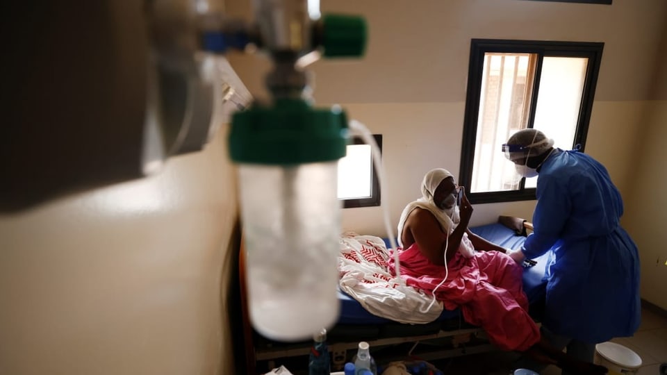 Eine Frau wird beatmet. In Senegal. Der Arzt trägt einen Mundschutz.