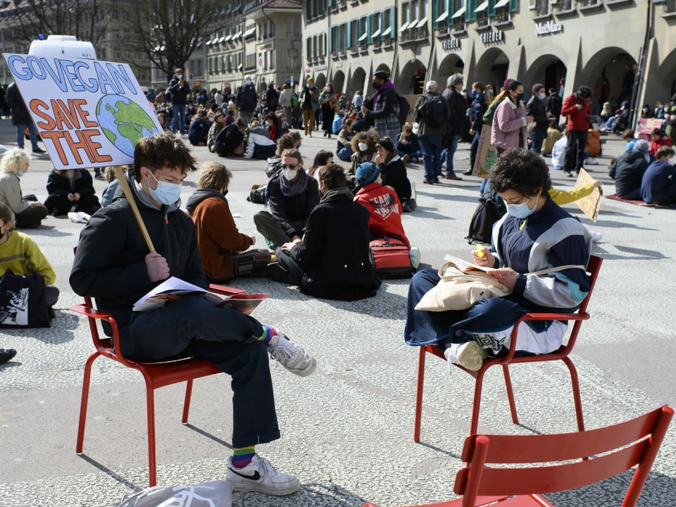 Zwei Demonstrierende sitzen auf Stühlen und lesen.