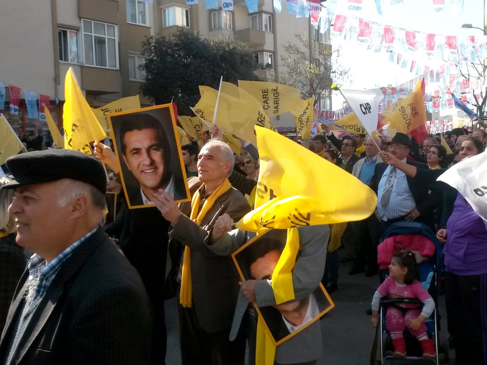 Menschen mit gelben Fahnen und Schildern mit Mustafa Sarigül.