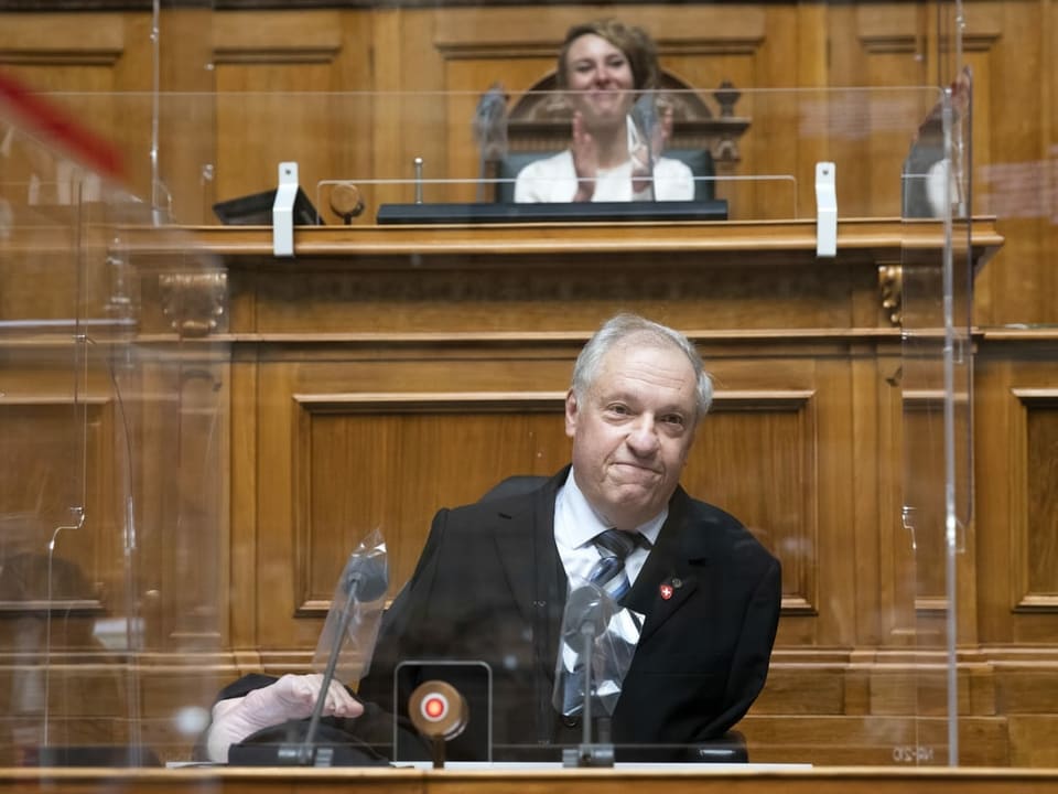 Nationalrat Christian Lohr sitzt am Rednerpult. Er hat weder ausgebildeten Arme noch Beine und sitzt im Rollstuhl.