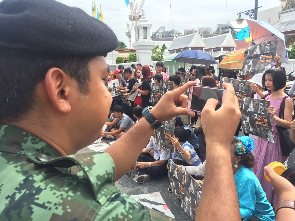 Ein Polizist fotografiert die Demonstranten.