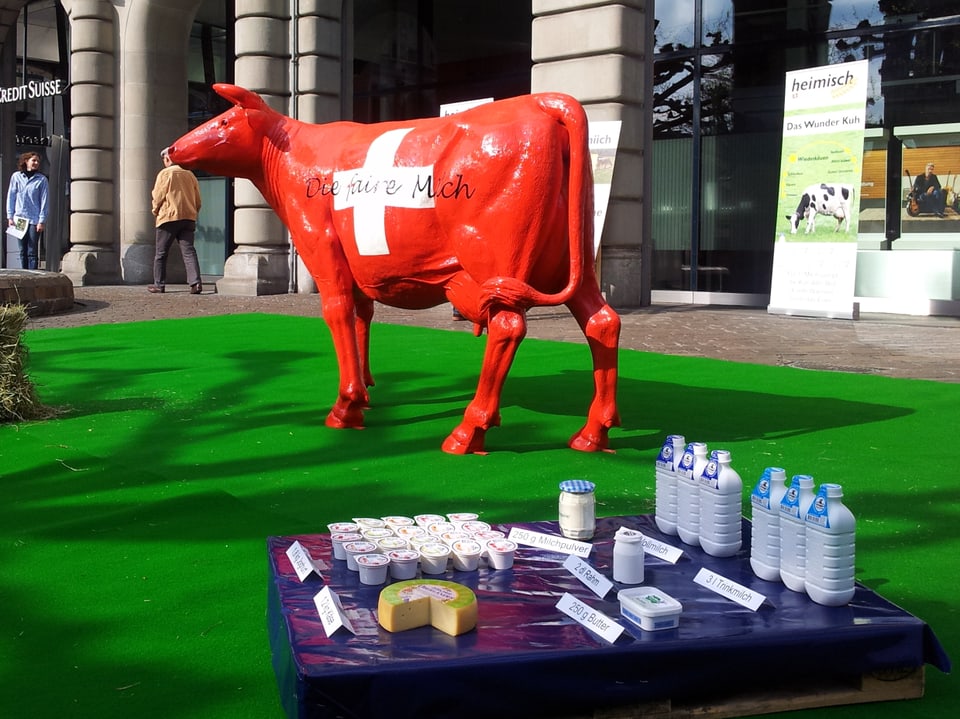Eine rote Plastikkuh mit Schweizerkreuz, im Vordergund Milchprodukte von Zürcher Bauern.