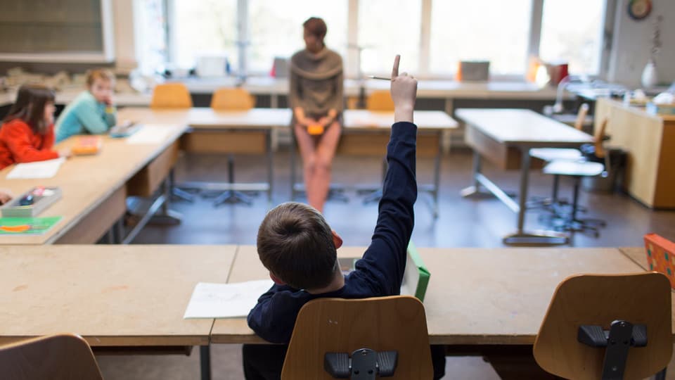 Ein Schüler hebt die Hand im Unterricht.