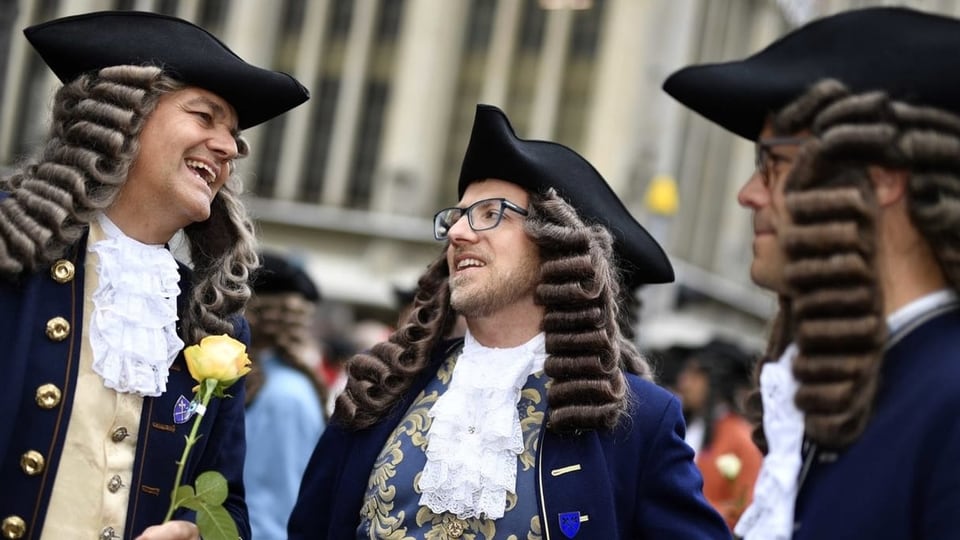 Männer in historischen Gewändern und mit Perücke am Zürcher Sechseläutenumzug