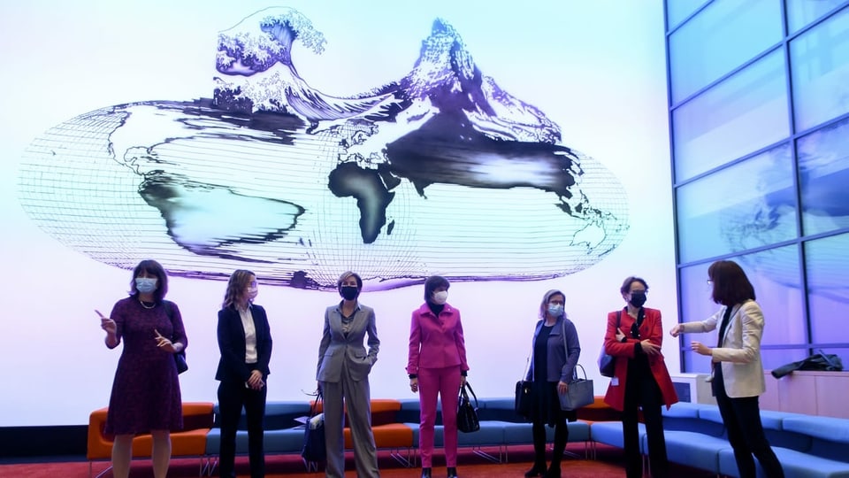 Sieben Frauen stehen vor einem Screen.