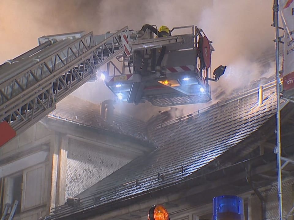 Feuerwehrleute versuchen das Feuer auf dem Dach zu löschen.