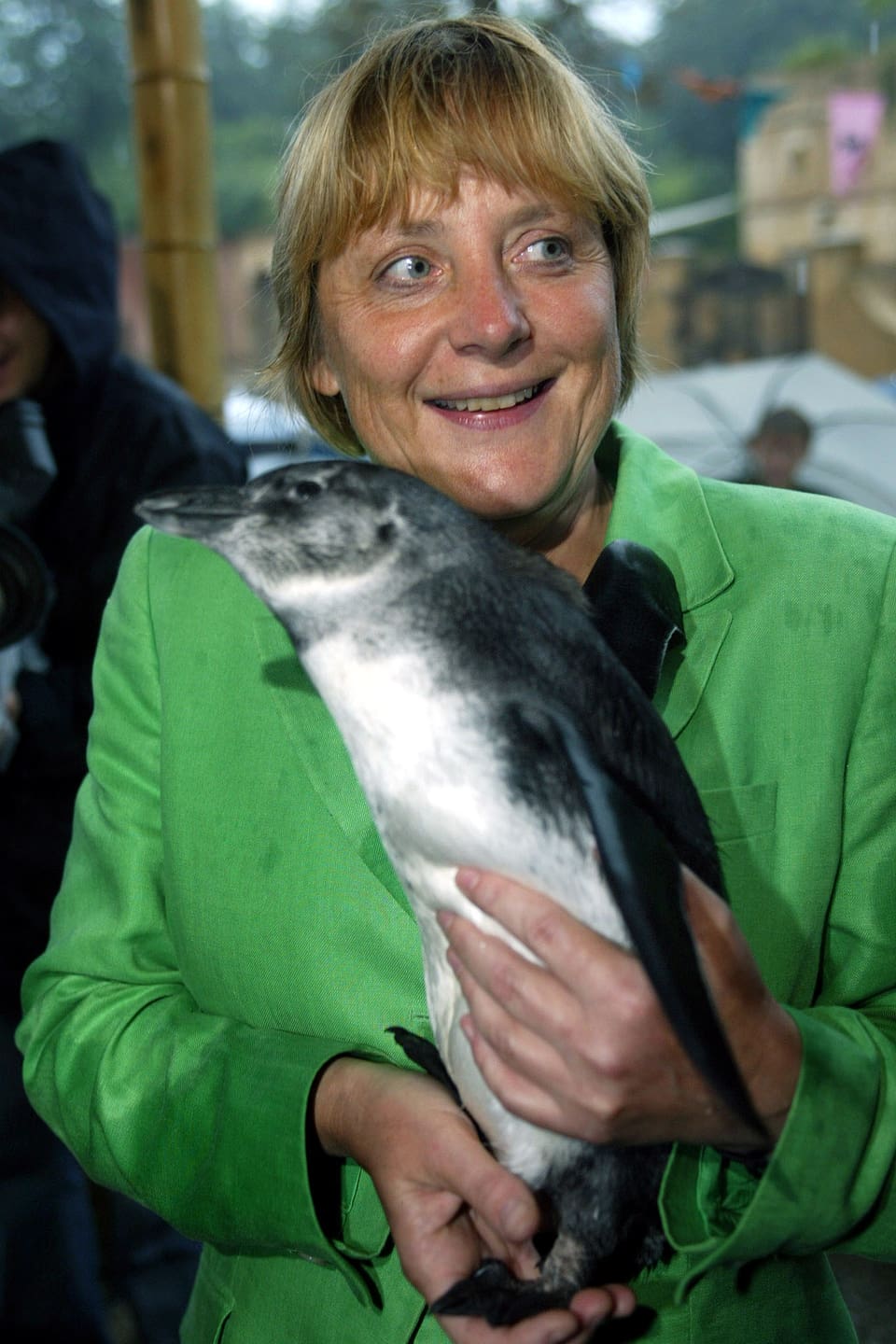 Angela Merkel mit einem Pinguin in der Hand.