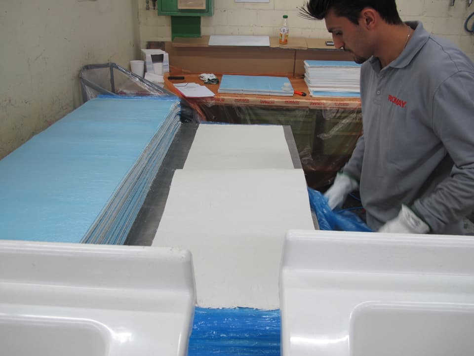 Ein Mitarbeiter schneidet Kunststoffmatten für ein Lavabo zurecht.