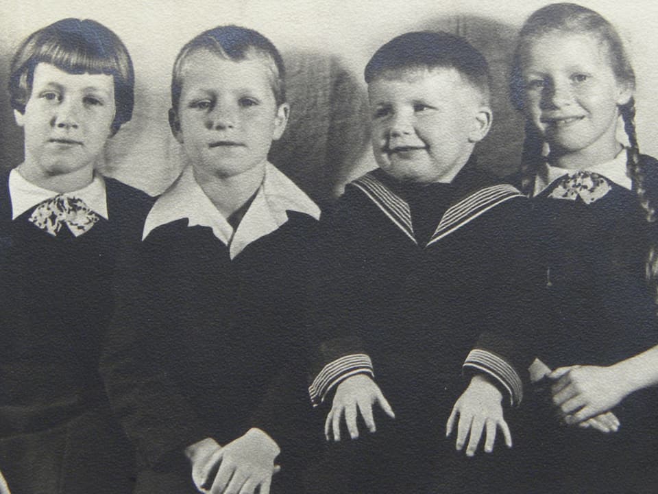 Schwarz-Weiss Fotografie mit vier Kindern, die in einer Reihe sitzen.