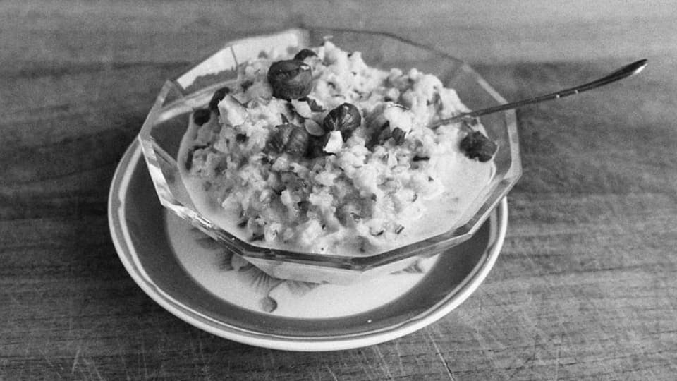 schwarz-weiss Foto Schüssel auf Unterteller, darin Birchermüesli mit Nüssen.