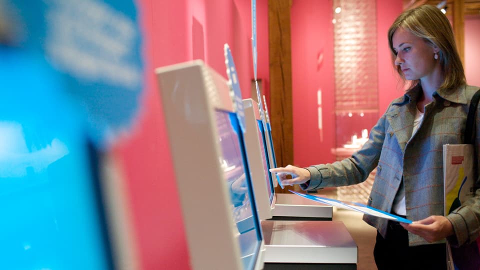 Eine Frau bedient eine «Teststation» mittels Fingerberührung.