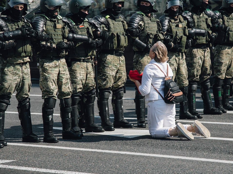 Eine Frau kniet vor einer Reihe Soldaten. 