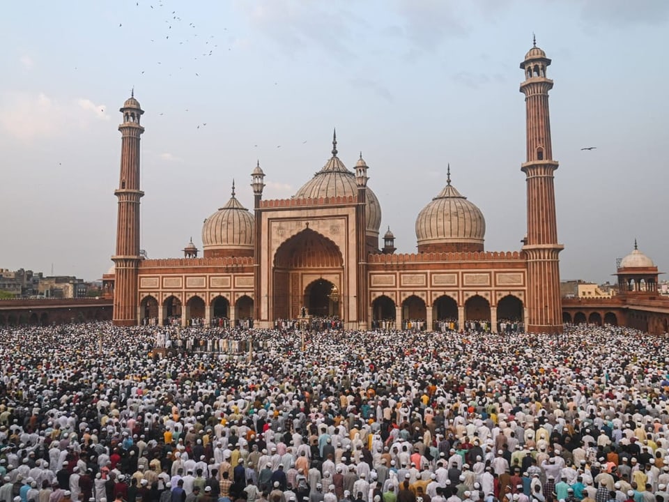 Hunderte oder Tausende beten vor einer Moschee. 