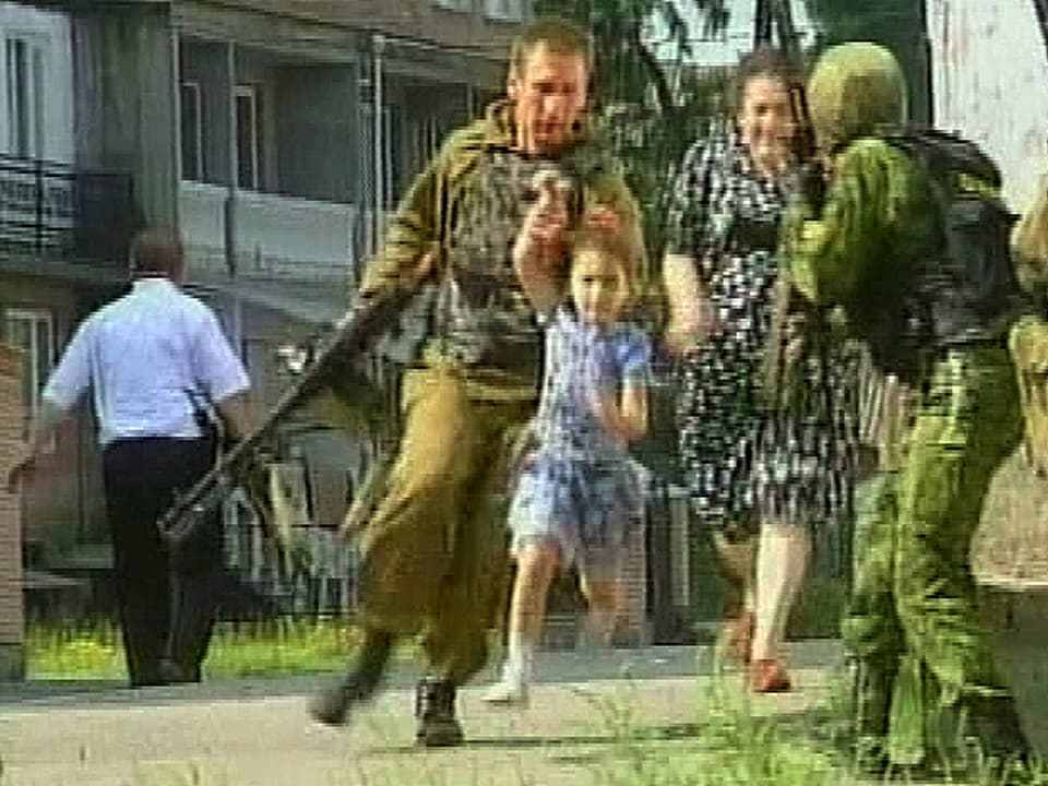 Bewaffnete Soldaten führen ein Mädchen und eine Frau von einer Schule weg.