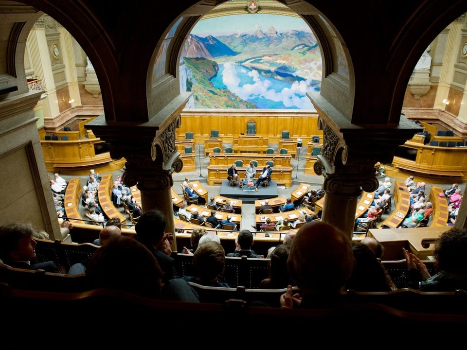 Blick auf den Nationalratssaal mit Zuschauern und der Gesprächsrunde vorne.