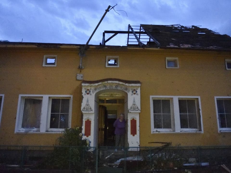 Frau vor Gebäude mit abgerissenem Dach