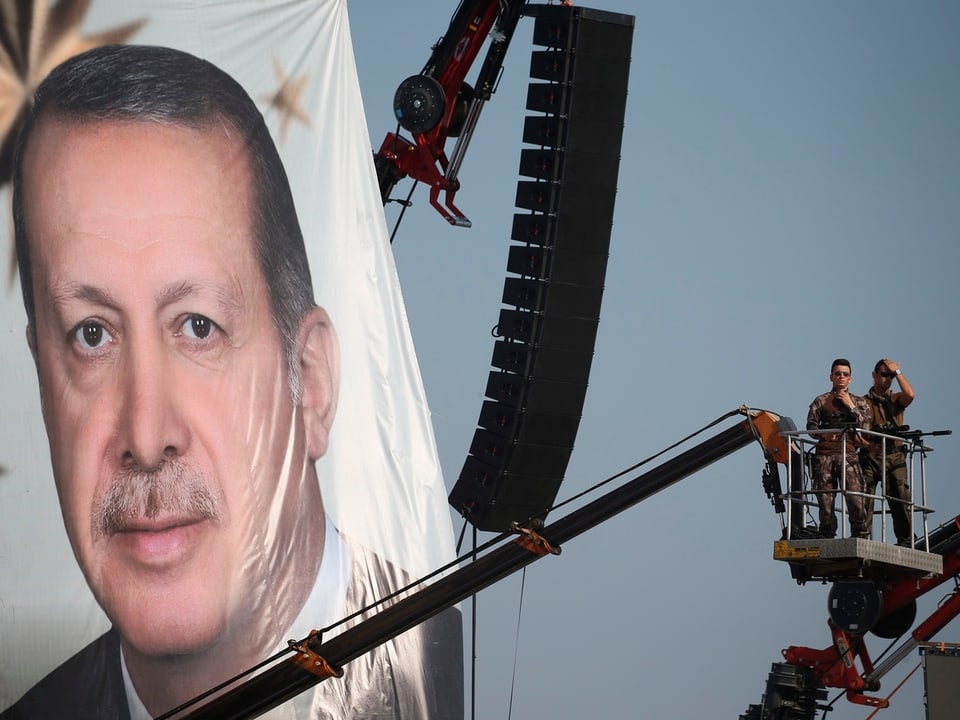 Sicherheitskräfte auf einem Kran, daneben hängt ein riesiges Portrait Erdogans