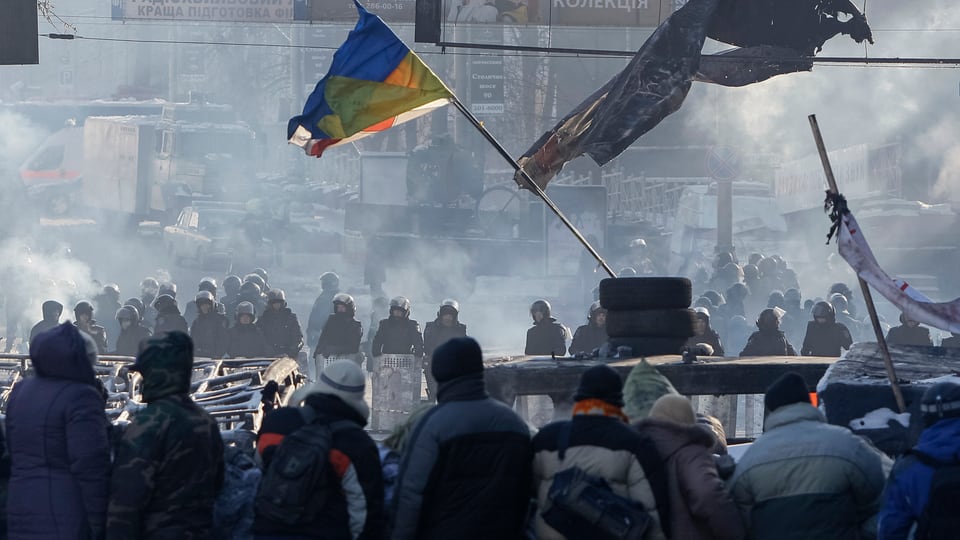 Demonstranten auf einer Strasse mit einer Ukrainen-Fahne.