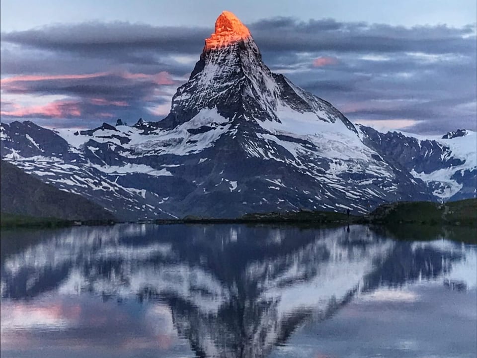 Sonnenaufgang mit Matterhorn mit roter Spitze, das sich in Bergsee spiegelt.