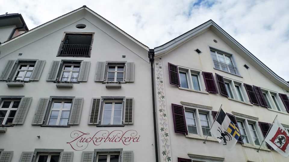 Fassaden zweier alten Gebäude mit zwei Fahnen, einmal Graubünden einmal Chur.