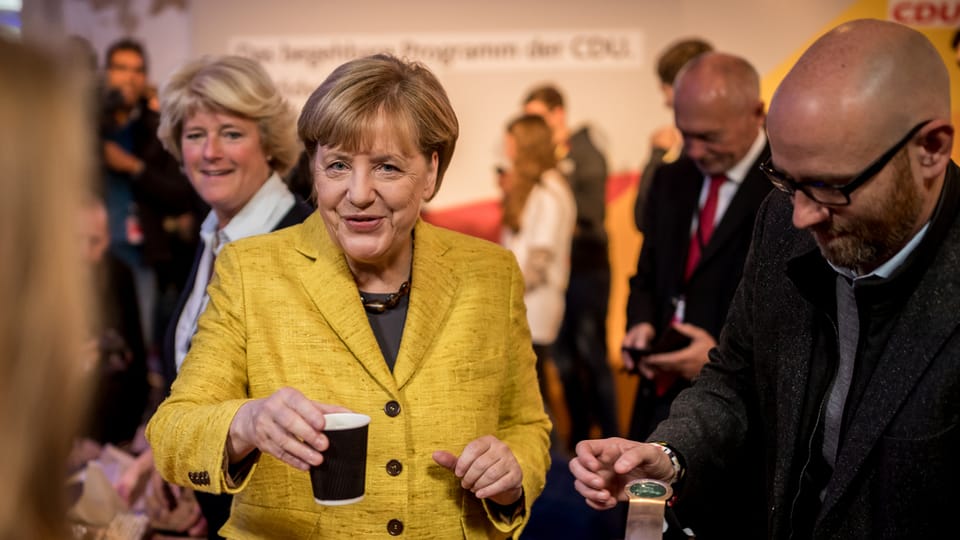 Merkel verteilt Kaffee.