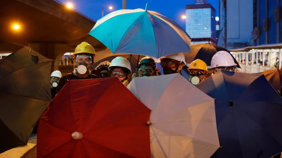 Demonstranten schützen sich mit Regenschirmen.
