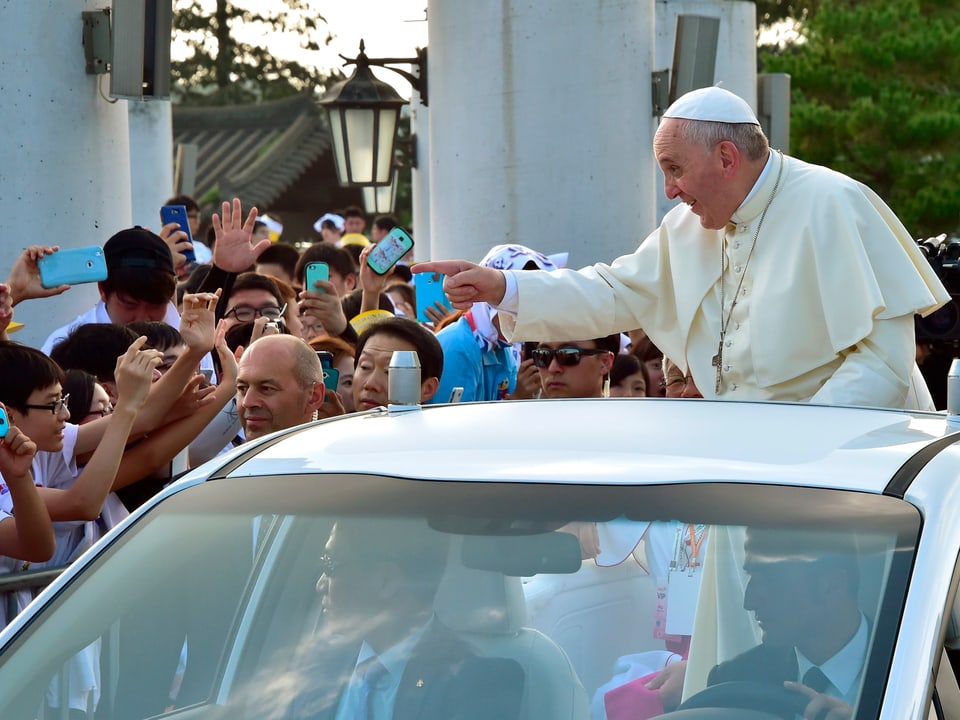 Der Papst in einem Auto stehend.