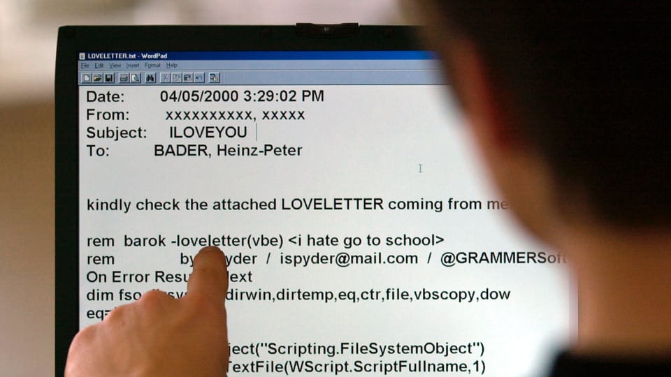 Ein Mann zeigt mit dem Finger auf verdächtigen Programmcode in einem E-Mail.