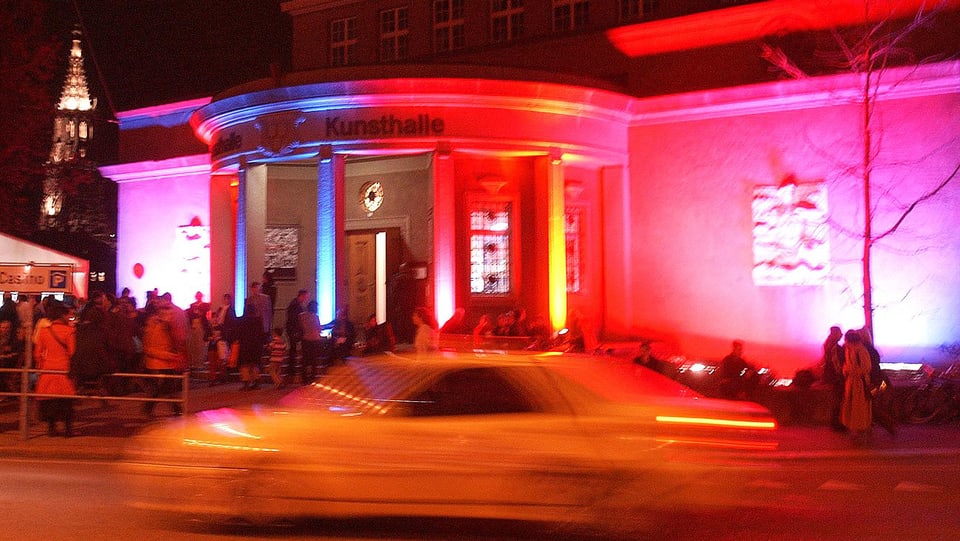 Aussenansicht der Kunsthalle Bern. Sie ist in blaues, rotes und pinkes Licht getaucht.