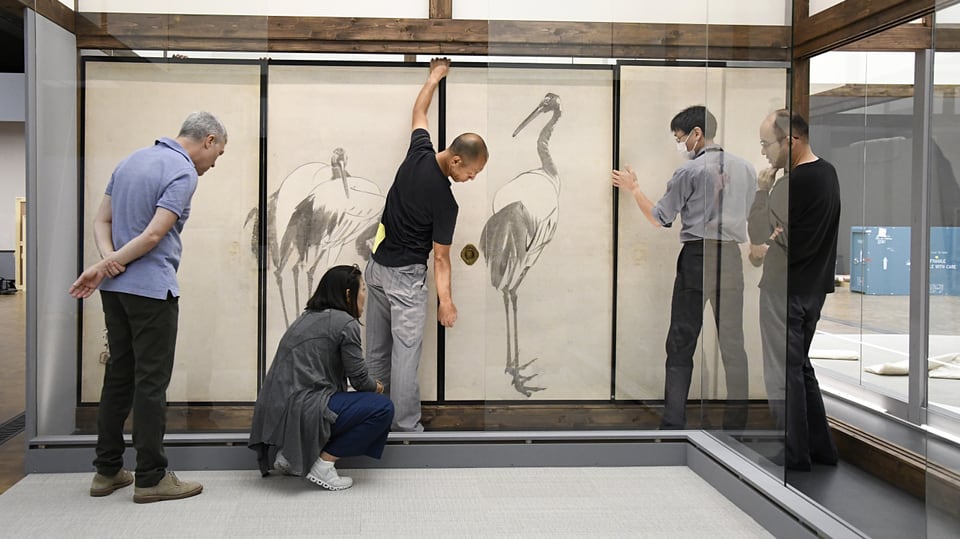 Fünf Personen bauen eine Zeichnung mit einem Vogel auf