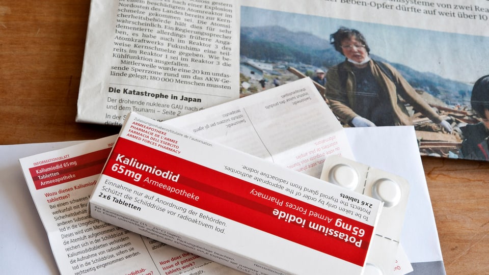 Ein Pack Jodtabletten liegt auf einer Zeitung mit einem Bericht zum Unglück in Fukushima.